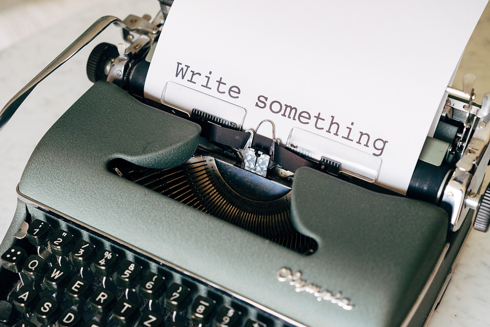 Imagen de una máquina de escribir. En el papal que sobresale pone «Write something» (Escribe algo)