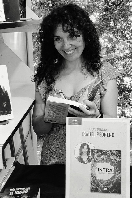 Fotografía en blanco y negro de Isabel Pedrero firmando un ejemplar de Intra en un evento